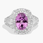 An 18K White Gold Pink Sapphire and Diamond Ring, designed as a Cocktail Ring, featuring a 5.04 Carat Oval Pink Sapphire center stone surrounded by a halo of Round and Baguette diamonds (0.94 CTW total).
