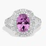 An 18K White Gold Pink Sapphire and Diamond Ring, designed as a Cocktail Ring, featuring a 5.04 Carat Oval Pink Sapphire center stone surrounded by a halo of Round and Baguette diamonds (0.94 CTW total).