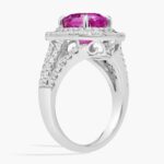 An 18K White Gold Pink Sapphire and Diamond Ring, designed as a Cocktail Ring, featuring a 5.04 Carat Oval Pink Sapphire center stone surrounded by a halo of Round and Baguette diamonds (0.94 CTW total).