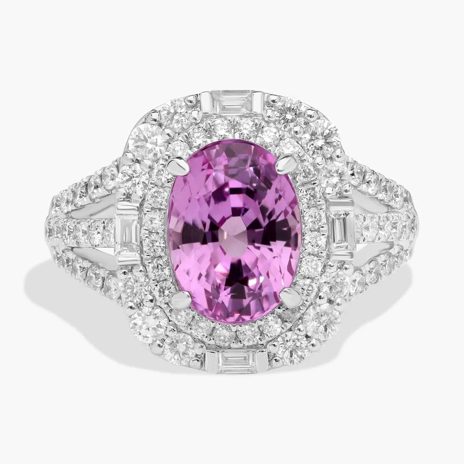An 18K White Gold Pink Sapphire and Diamond Ring, designed as a Cocktail Ring, featuring a 5.04 Carat Oval Pink Sapphire center stone surrounded by a halo of Round and Baguette diamonds (0.94 CTW total).
