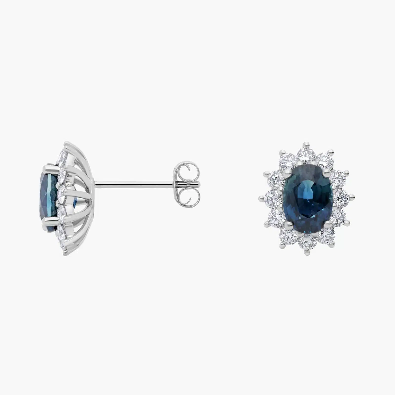 oval-sapphire-diamond-halo-white-gold-and-sapphire-earrings-18k-0-72ctw 2 An 18K White Gold White Gold and Sapphire Earrings set featuring two 7x5 mm Oval Blue Sapphires surrounded by a 0.72 CTW Round Diamond Halo, secured with Push Backs.