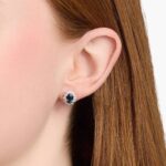 An 18K White Gold White Gold and Sapphire Earrings set featuring two 7x5 mm Oval Blue Sapphires surrounded by a 0.72 CTW Round Diamond Halo, secured with Push Backs.