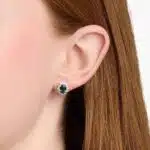 An 18K White Gold White Gold and Sapphire Earrings set featuring two 7x5 mm Oval Blue Sapphires surrounded by a 0.72 CTW Round Diamond Halo, secured with Push Backs.