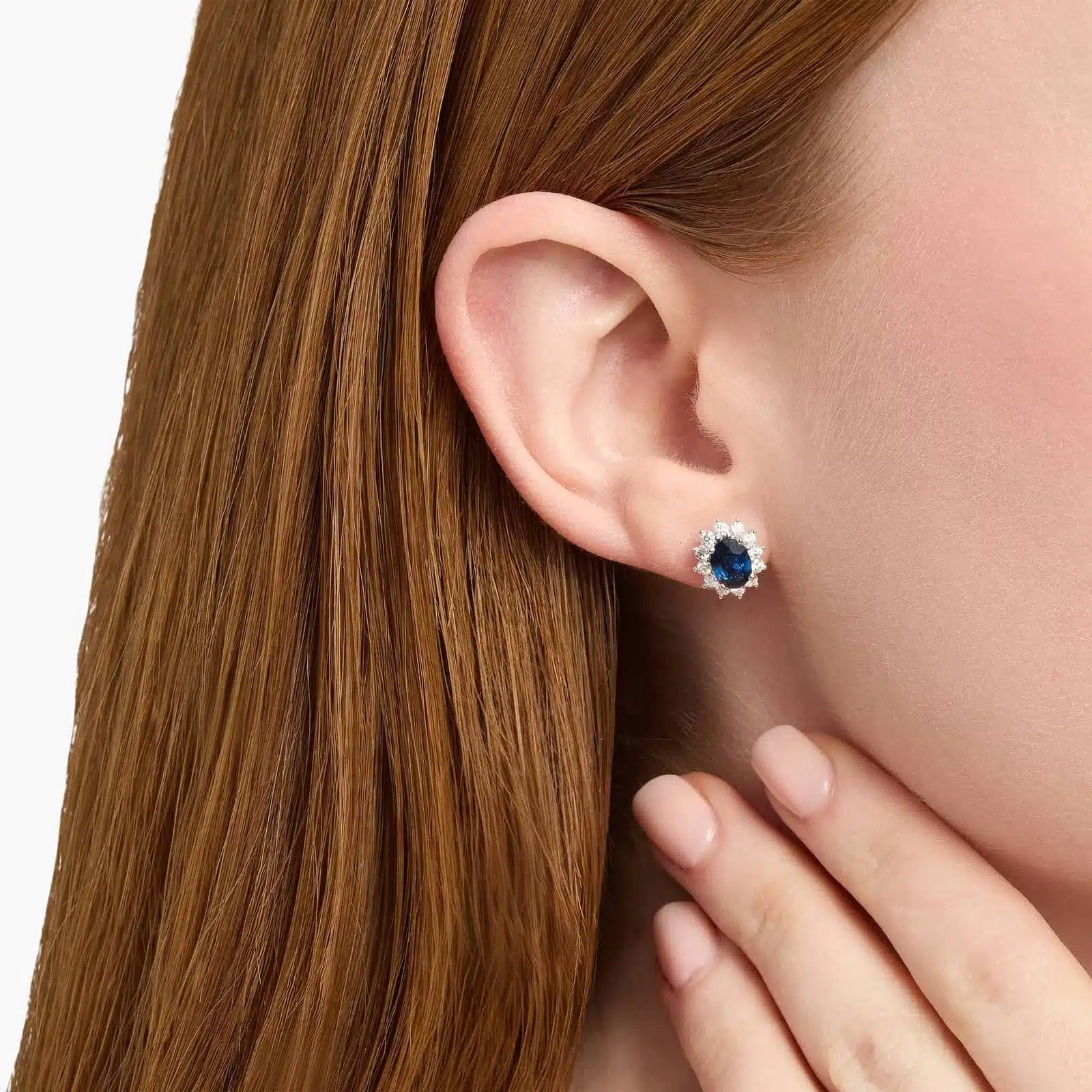 oval-sapphire-diamond-halo-white-gold-and-sapphire-earrings-18k-0-72ctw model view An 18K White Gold White Gold and Sapphire Earrings set featuring two 7x5 mm Oval Blue Sapphires surrounded by a 0.72 CTW Round Diamond Halo, secured with Push Backs.