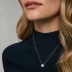 14K white gold blue sapphire pendant necklace featuring a 0.48 carat oval blue sapphire center stone and a pavé diamond halo on an 18-inch rolo chain.