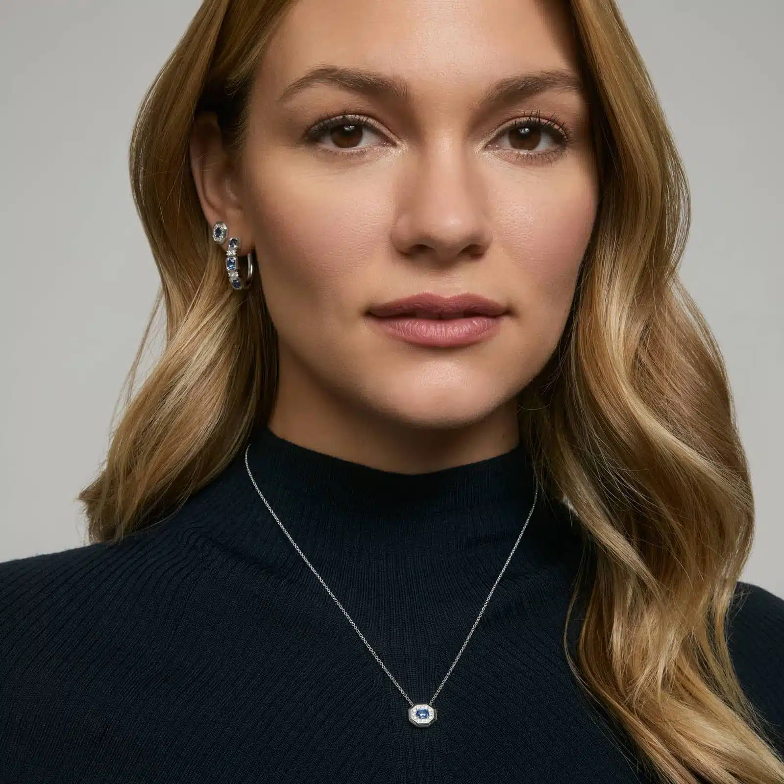 pave-diamond-and-oval-blue-sapphire-pendant-necklace-14k-white-gold model view 2 14K white gold blue sapphire pendant necklace featuring a 0.48 carat oval blue sapphire center stone and a pavé diamond halo on an 18-inch rolo chain.