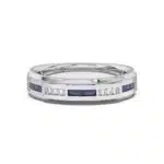 An 18K White Gold Women's Baguette Wedding Band featuring an alternating channel-set pattern of Baguette Blue Sapphires and Round Diamonds (0.06 CTW). The band tapers in width.