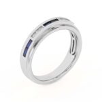 An 18K White Gold Women's Baguette Wedding Band featuring an alternating channel-set pattern of Baguette Blue Sapphires and Round Diamonds (0.06 CTW). The band tapers in width.