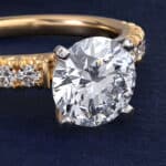 14K yellow gold French pavé engagement rings under $2,500 featuring a 1 carat round lab grown diamond and 16 natural diamond accents.