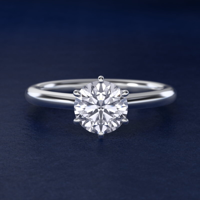 Platinum six prong solitaire engagement rings under $2,500 featuring a 1.5 carat round colorless lab grown diamond on a petite 1.80mm Nouveau band.