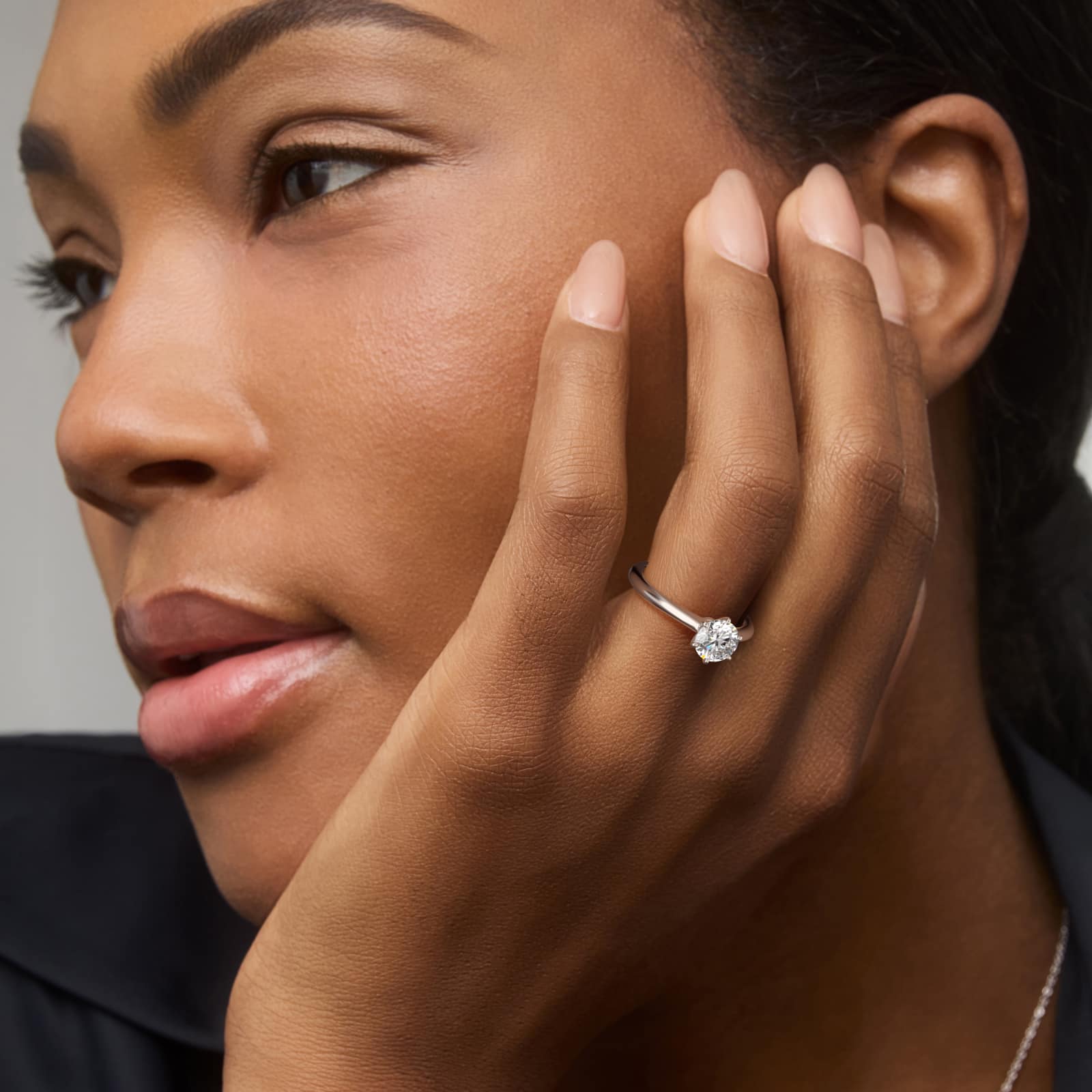 Platinum six prong solitaire engagement rings under $2,500 featuring a 1.5 carat round colorless lab grown diamond on a petite 1.80mm Nouveau band.