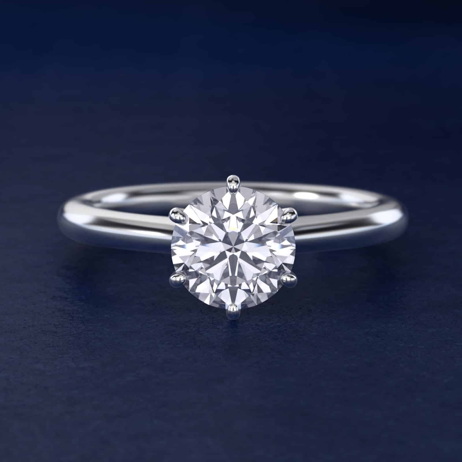 Platinum six prong solitaire engagement rings under $2,500 featuring a 1.5 carat round colorless lab grown diamond on a petite 1.80mm Nouveau band.